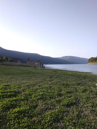 a grassy field next to a body of water at Mavrovo Kjara Apartments in Mavrovo