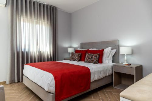 a bedroom with a large bed with red pillows at AZUL in Zambujeira do Mar