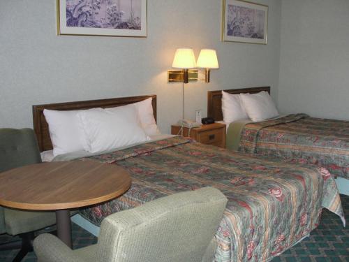 a hotel room with two beds and a table and chair at Budget Inn in Alcoa