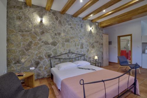 a bedroom with a bed and a stone wall at Apartments Stipe in Lukovo