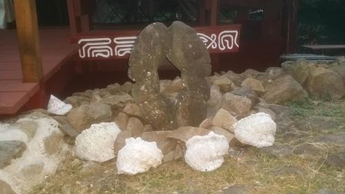 a pile of rocks and a statue in a yard at Location " la Pirogue " Maison d'Hôtes à Moorea in Haapiti