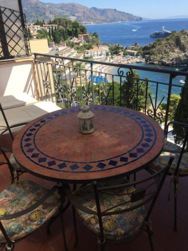 a table on a balcony with a view of the ocean at ToviMar Apartments in Taormina