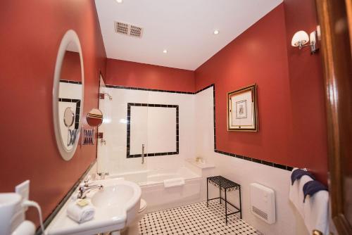 a bathroom with red walls and a sink and a tub at Manoir Sherbrooke in Montréal