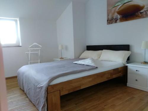 a white bedroom with a large bed and a window at Haus am Schlossbach**** in Brannenburg