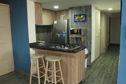 cocina con fogones, nevera y taburetes en Apartamento de tres habitaciones en zona centro de San Andrés Islas - Edificio Comodoro 203, en San Andrés