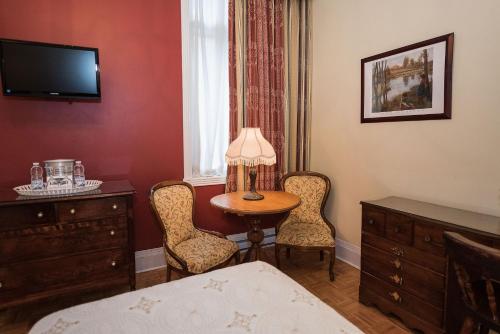 a bedroom with a table and two chairs and a bed at Manoir Sherbrooke in Montréal