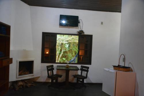 a room with a table and a window with a tv at Pousada Moinho Azul in Teresópolis