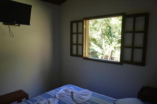 a bedroom with a bed and a window at Pousada Moinho Azul in Teresópolis