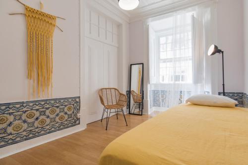 a bedroom with a bed and a chair and a window at Blue Tiles in City Center in Lisbon