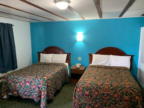 Habitación de hotel con 2 camas y pared azul en Mayo Inn en Roswell