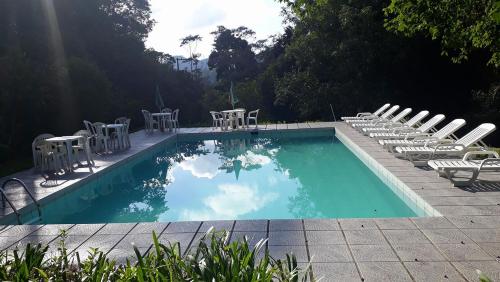 a swimming pool with chairs and a bunch ofitures at Pousada Moinho Azul in Teresópolis
