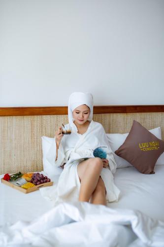 a woman sitting on a bed in a towel at Luu Ngai Condotel Quy Nhon in Quy Nhon