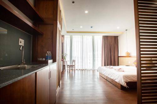 a bedroom with a bed and a kitchen with a sink at Luu Ngai Condotel Quy Nhon in Quy Nhon