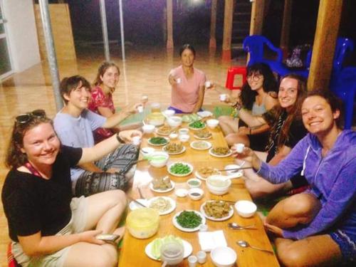 Eine Gruppe von Menschen, die an einem Tisch sitzen und essen in der Unterkunft Ngọc Thúy Homestay Mù Cang Chải in Lao San Chay