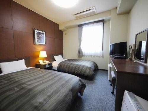 a hotel room with two beds and a television at Hotel Route-Inn Kamisuwa in Suwa