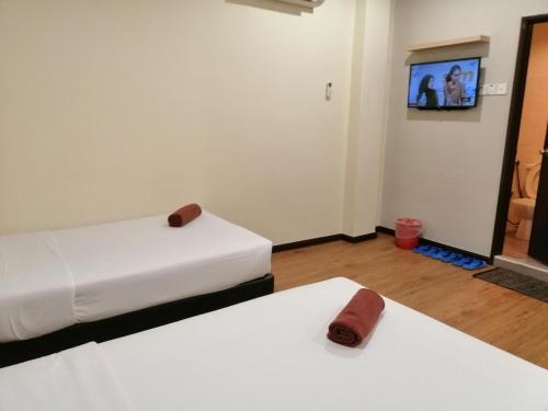 two beds in a room with a tv on the wall at Northern Lodge Hotel in Sungai Petani