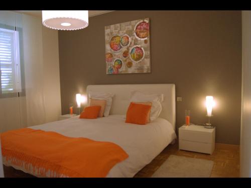 ヴィルヌーヴ・ルベにあるLes Hauts de Vaugrenierのベッドルーム1室(オレンジ色の枕と絵画付)