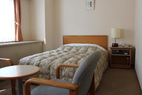 ein Schlafzimmer mit einem Bett, einem Tisch und einem Stuhl in der Unterkunft Hotel Tetora Makuhari Inagekaigan (Formerly Business Hotel Marine) in Chiba