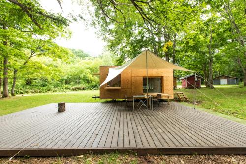 a tent on a wooden deck in a park at Snow Peak Jyubako（AKAIGAWA TOMO PLAYPARK） in Akaigawa