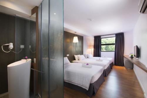 a hotel room with two beds and a glass wall at T+ Hotel Butterworth in Butterworth