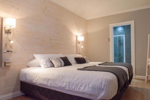 a bedroom with a large white bed with a wooden wall at Hostal Boutique Puerta Roja in Punta Arenas