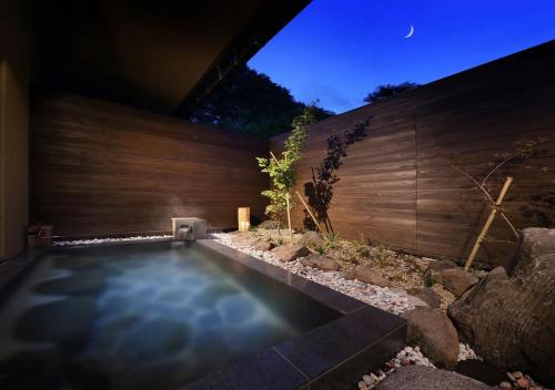 a swimming pool in a backyard with a wooden wall at Oyado Morinone in Kaminoyama