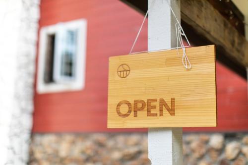 a wooden sign with the word open hanging in front of a house at Snow Peak Jyubako（AKAIGAWA TOMO PLAYPARK） in Akaigawa