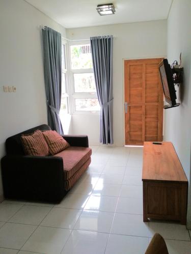 a living room with a couch and a table and a window at Wisma Andany in Jepara