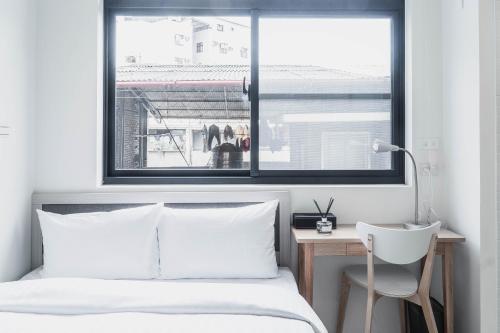 a bedroom with a bed and a desk and a window at Boléro Homestay I 鄰近花園夜市 in Tainan