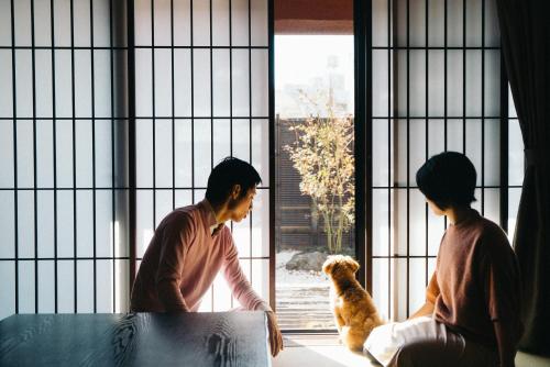 two people and a dog looking out of a window at Wacasa 旅音 in Kanazawa