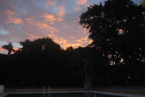 a sunset in the sky with trees and a pool at Hotel Diriá Santa Cruz in Santa Cruz
