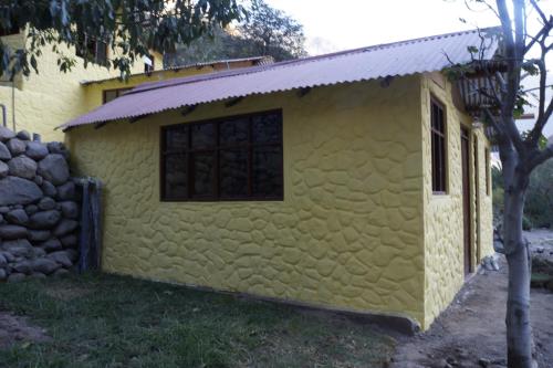 a small yellow building with a window and a fence at Paraiso Las Palmeras Lodge in Cabanaconde