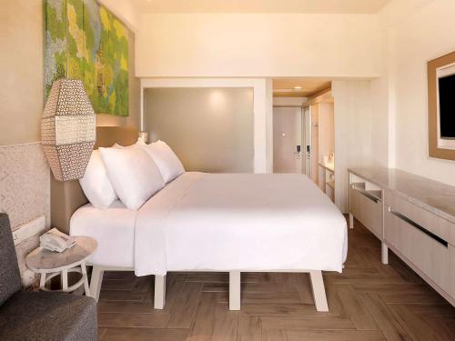 a bedroom with a white bed in a room at Mercure Kuta Bali in Kuta