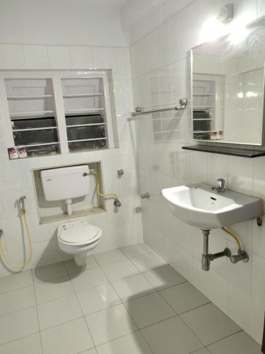 a white bathroom with a toilet and a sink at YWCA International Centre in Mumbai