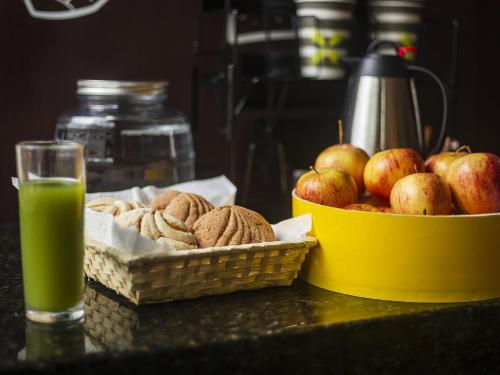 a table with two baskets of apples and a glass of green juice at Hotel Via La Villa in Mexico City