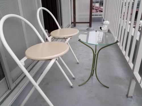 two chairs and a glass table on a porch at FukuokaKoryou GuestHouse in Fukuoka