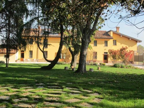 ローディにあるAgriturismo Cascina Pezzoloの田んぼの木々が茂る大黄色い家