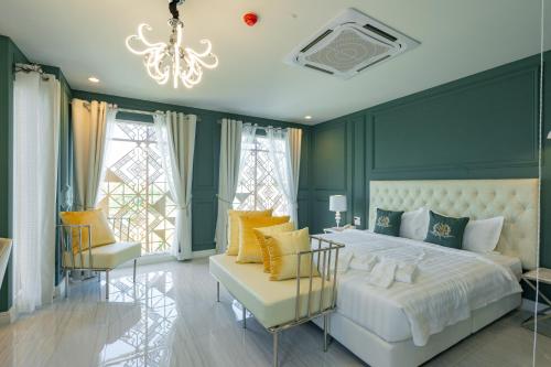 ウドーンターニーにあるBelle Grand Hotelの緑の壁のベッドルーム(白いベッドと椅子付)