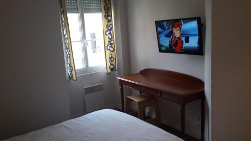a bedroom with a desk and a television on the wall at Au Pigeon Blanc in Andouillé