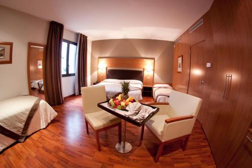 ein Hotelzimmer mit einem Bett und einem Tisch mit Obst darauf in der Unterkunft Alti Hôtel in Luchon