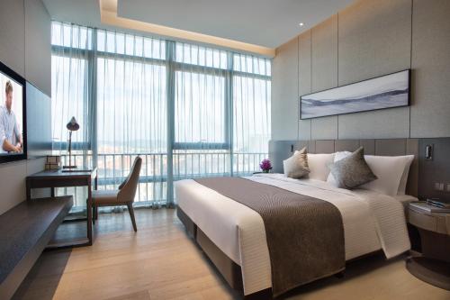 a bedroom with a large white bed and a desk at Ascott Songshan Lake Dongguan in Dongguan