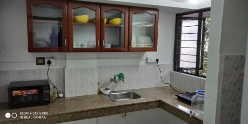 a kitchen counter with a sink and a microwave at Andoor Homes, Apt No 2B in Trivandrum