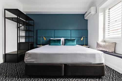 a bedroom with a large bed with blue walls at Avoca Randwick by Sydney Lodges in Sydney