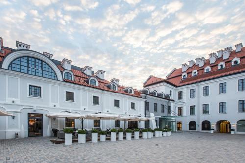 a large white building with umbrellas in a courtyard at Hotel Pacai, Vilnius, a Member of Design Hotels in Vilnius
