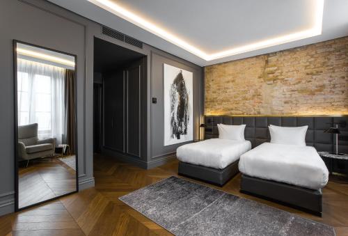 a bedroom with two beds and a brick wall at Hotel Pacai, Vilnius, a Member of Design Hotels in Vilnius