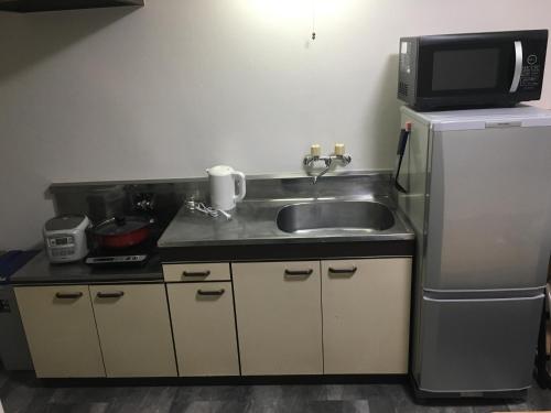 a kitchen with a sink and a microwave and a refrigerator at コンドミニアムホテル Stay inn Blue in Hukue