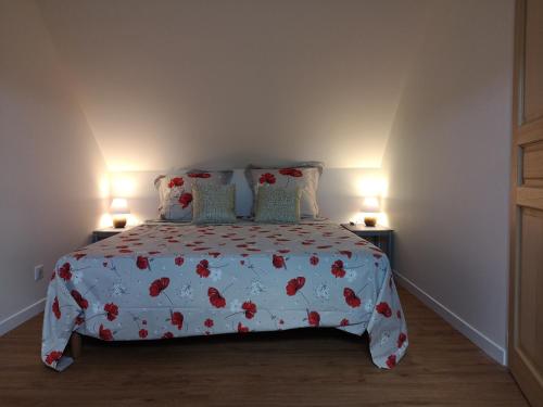 una camera da letto con un letto con copriletto floreale e 2 lampade; di maison entre campagne et mer a Plonéour-Lanvern