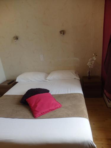 a bedroom with two white beds with a pink pillow at le relais des forêts in Blessac