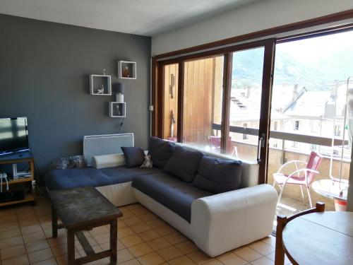 sala de estar con sofá y ventana grande en APPARTEMENT 4 PERSONNES A 500M DES TELECABINES, en Briançon