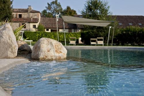 a pool of water with rocks and an umbrella at Agriturismo La Montecchia in Selvazzano Dentro